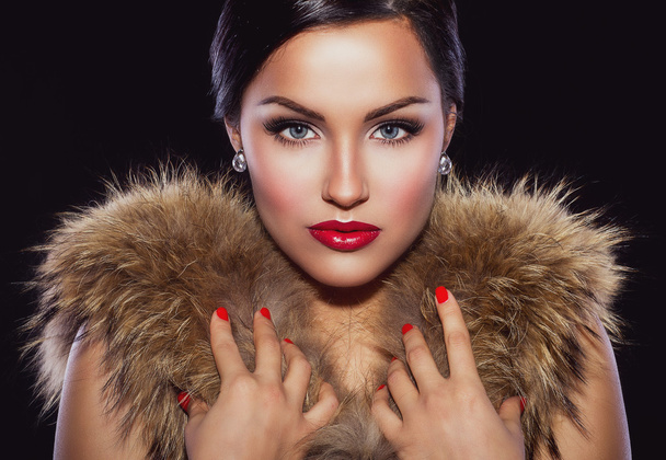 Beautiful brunette holding her hands on fur - Photo, Image