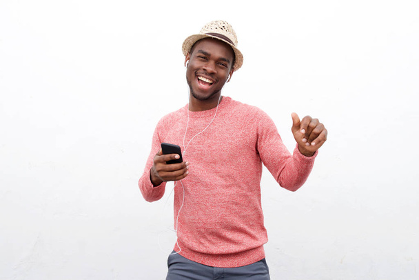 Portret mężczyzny w african american szczęśliwy słuchania muzyki za pomocą słuchawek i telefonu komórkowego na białym tle - Zdjęcie, obraz
