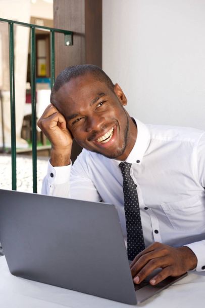 Portrét šťastný africké americké obchodní muž sedící u stolu s přenosným počítačem  - Fotografie, Obrázek