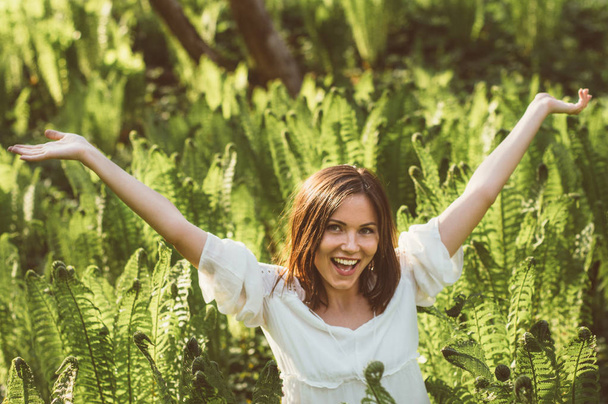 Mooie verrukking brunette meisje handen omhoog in fern - Foto, afbeelding