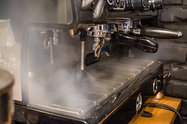 Work the barista in coffee shop on the coffee machine. The steamer is on. Hot steam. Processing. Dark background. - Fotografie, Obrázek
