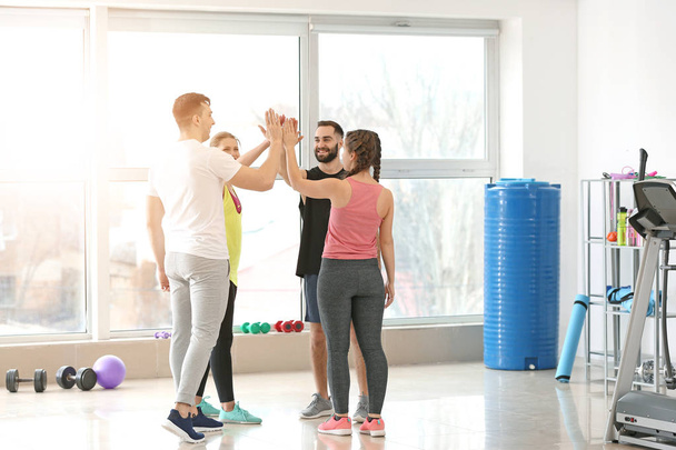 Sportieve jonge mensen brengen handen samen in Gym - Foto, afbeelding