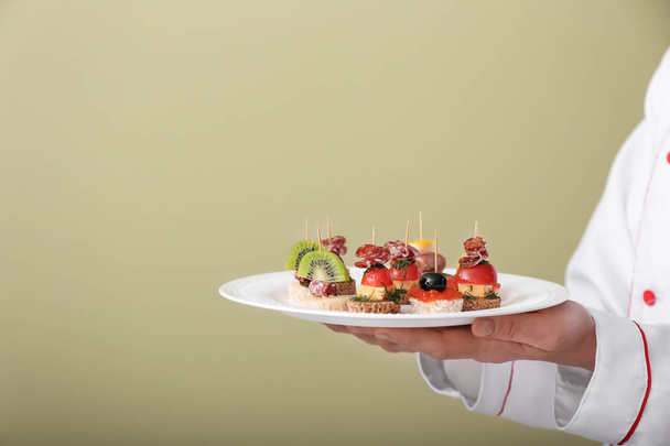 Kuchař, drží desku s chutné jednohubky na barvu pozadí - Fotografie, Obrázek