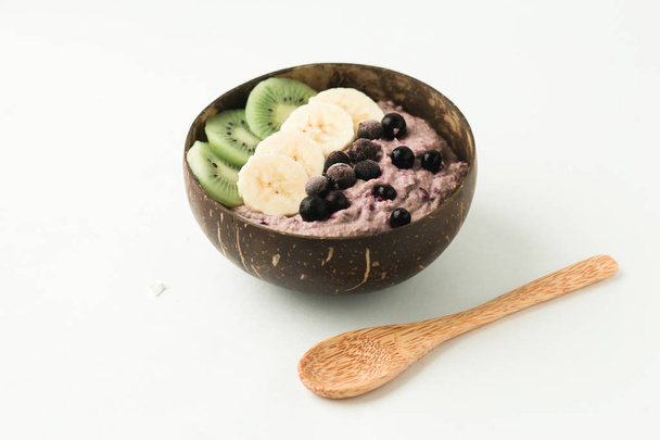Smoothie saudável com frutas, prato feito de casca de coco e colher de madeira
 - Foto, Imagem