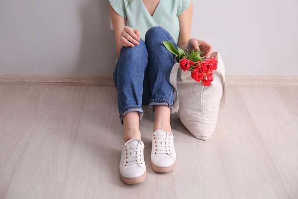 Eco bag with flowers near woman sitting on floor - Foto, Bild