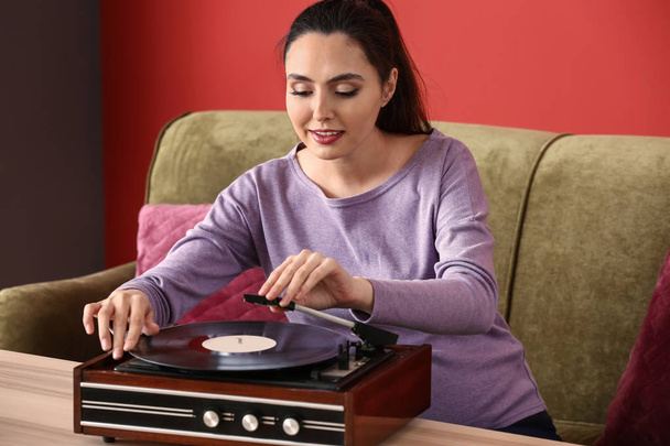 Pregnant woman listening to music through record player at home - Zdjęcie, obraz