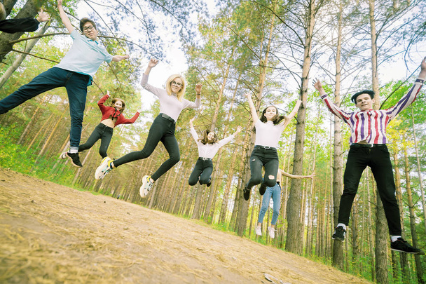 Jumping teenagers in a playful mood in the summer forest - Photo, Image