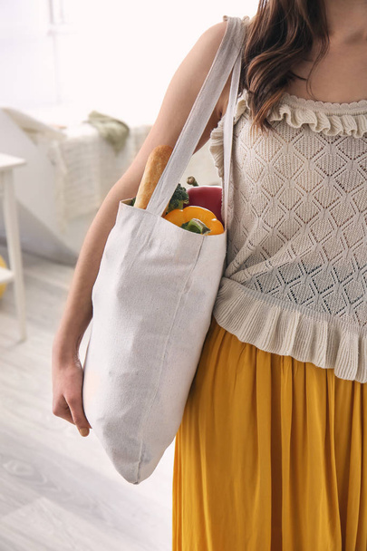 Young woman with fresh products in eco bag indoors - Foto, Bild