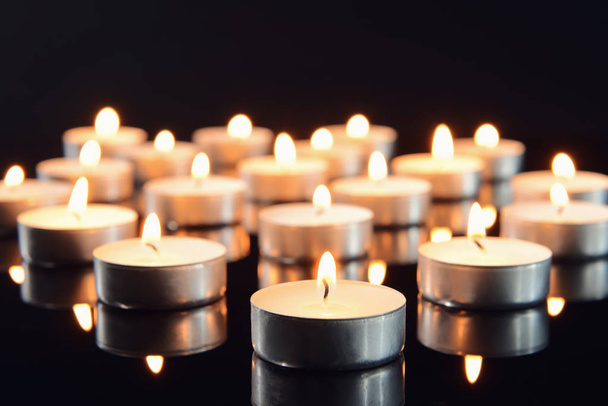 Viele brennende Kerzen als Symbol der Trauer auf dunklem Grund - Foto, Bild