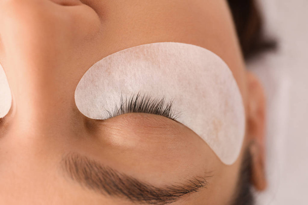 Young woman undergoing eyelash extension procedure in beauty salon, closeup - Valokuva, kuva