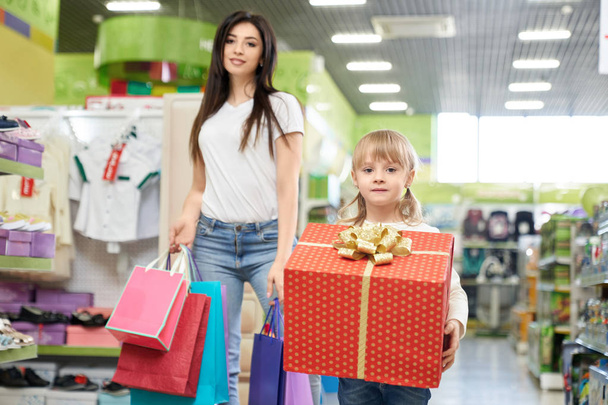 Mom and daughter in store with shopping bags and present box - Photo, image