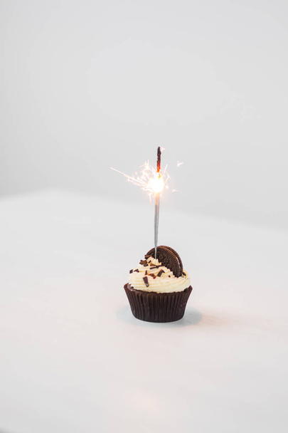 Їжа, пекарня, свято, щасливий день народження та концепція десертів - смачний кекс з іскристом та печивом на білому столі
 - Фото, зображення