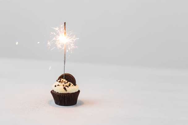 Food, party and holiday concept - Birthday cupcake with sparkler over white background with copy space - Photo, Image