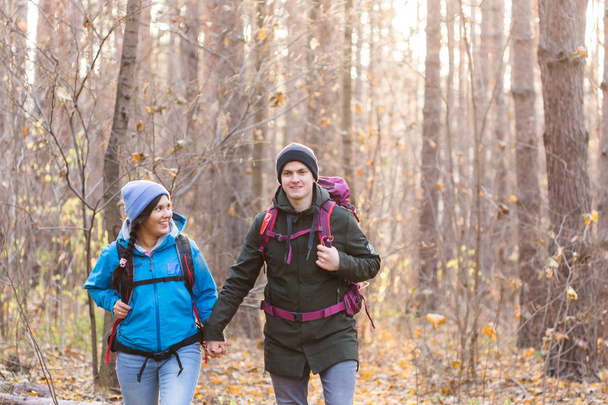 adventure, travel, tourism, hike and people concept - smiling couple walking with backpacks over autumn natural background - Photo, Image