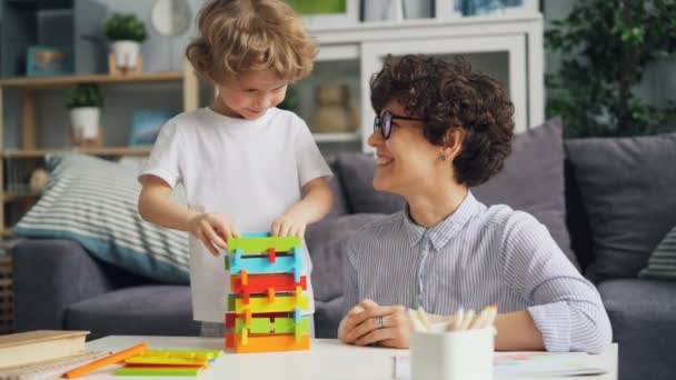 Cheerful girl mom playing with her little son with wooden blocks and laughing - Video