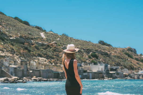 Portrait of girl in black dress staying by back on windy beach - Photo, Image
