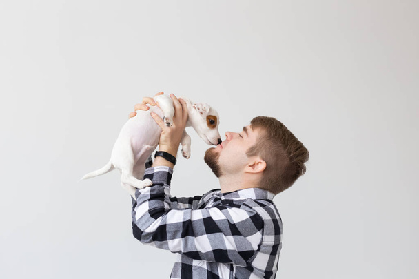 people, pets and animals concept - close up of young man holding jack russell terrier puppy on white background - Fotó, kép