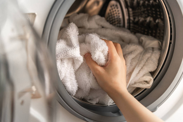 Primo piano di donna mano caricamento asciugamani bianchi in lavatrice
 - Foto, immagini