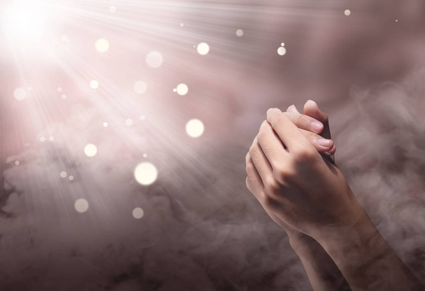 Mannelijke handen positie met ray bidden over onscherpe achtergrond - Foto, afbeelding