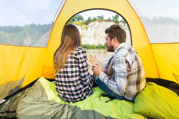 人、観光と自然の概念 - 黄色いテントの中で猫と座ってかわいいカップル - 写真・画像
