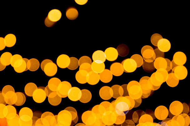 Unfocused abstract yellow bokeh on black background. defocused and blurred many round light - Photo, Image