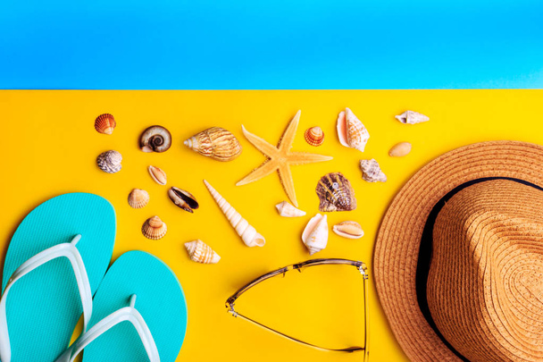 Seashells and stars. Straw hat and mint slippers on yellow and blue background. - Photo, Image