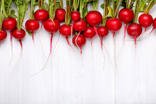 Fresh red radishes with tops in line on white wooden table.  - Valokuva, kuva