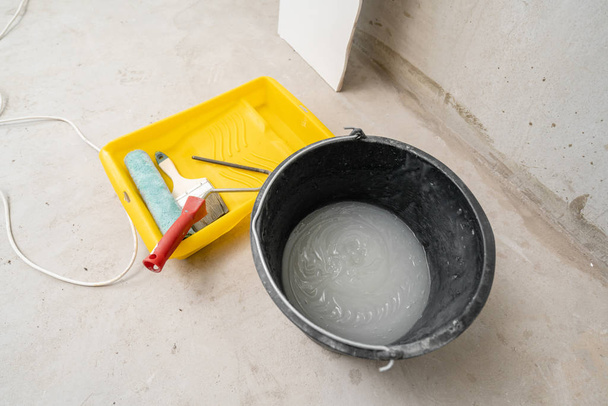 Pędzel, wałek i klej pojemnik na powierzchni betonu. Skład narzędzia do domu i wnętrza remonty wewnątrz. - Zdjęcie, obraz