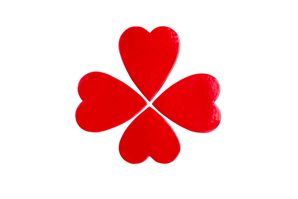 La imagen del símbolo feliz - el trébol de cuatro hojas con la ayuda de los corazones de cerámica. Símbolo de amor y buena suerte, Día de San Patricio. Arcilla, cubierta de esmalte rojo, doble cocción. Aislado sobre un blanco
 - Foto, imagen