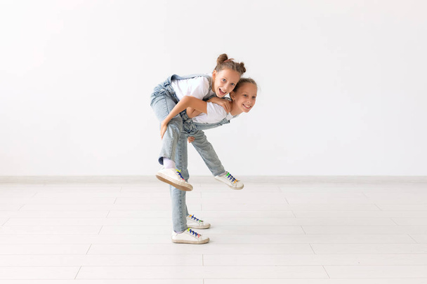 Familien- und Liebeskonzept - glückliches Zwillingsmädchen gibt ihrer lachenden Schwester Huckepack-Fahrt - Foto, Bild
