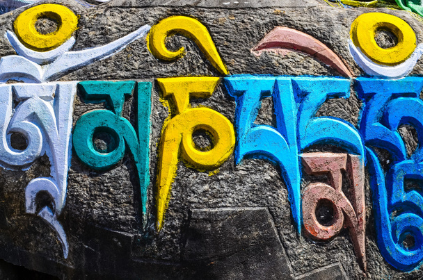 Símbolos religiosos budistas tibetanos em pedras
 - Foto, Imagem