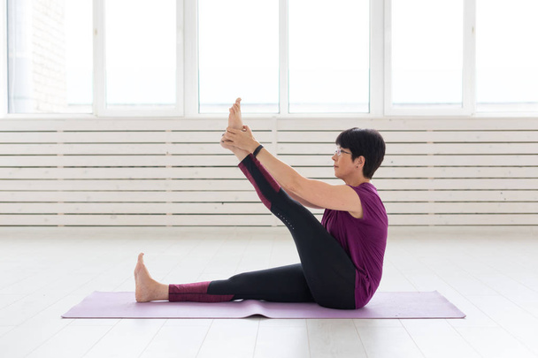 Yoga, concetto di persone - una donna di mezza età che fa yoga e cerca di fare un asana
 - Foto, immagini
