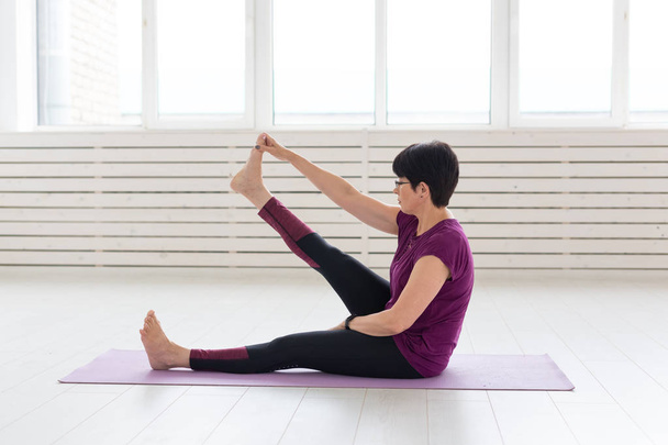 Yoga, conceito de pessoas - uma mulher de meia-idade fazendo um ioga e tentar fazer um asana
 - Foto, Imagem