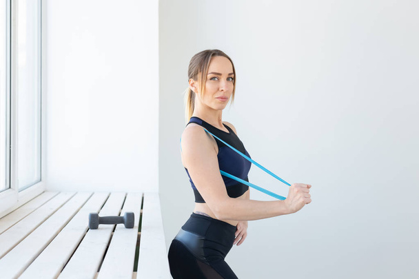 People, sport and fitness concept - young woman training with workout band in gym - Foto, afbeelding