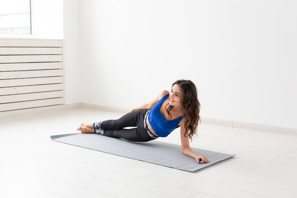 Estilo de vida saludable, personas y concepto deportivo - Mujer joven con el pelo rizado haciendo yoga sobre fondo blanco
 - Foto, imagen