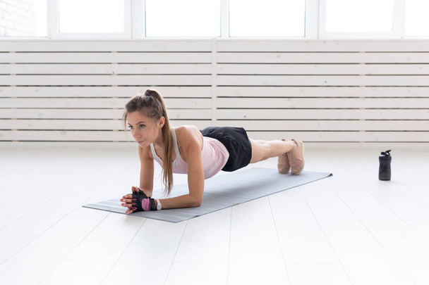 Sport, yoga and people concept - a young woman is doing a plank, taking a balance - Photo, Image