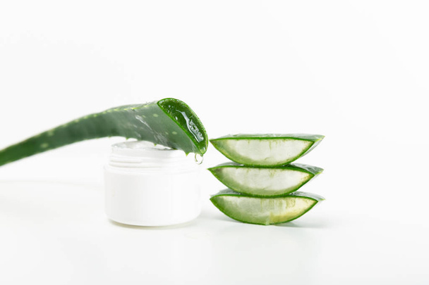 Sliced aloe vera leaf and cream bottle on a white background - Photo, Image