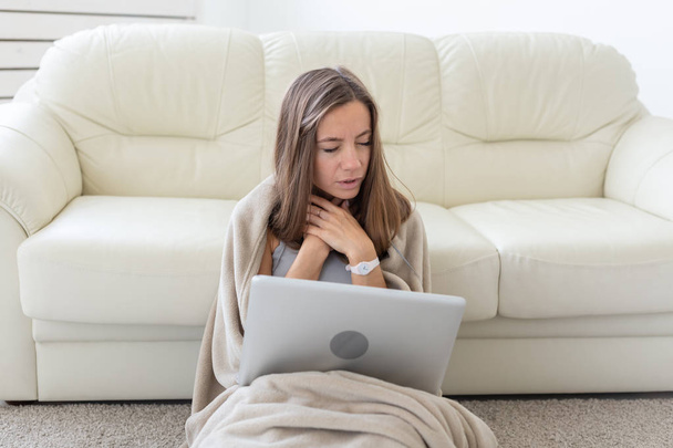 Donna con mal di gola seduta sul pavimento con computer portatile
 - Foto, immagini