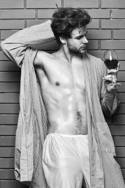 Guy attractive relaxing with alcohol drink. Bachelor enjoy wine. Macho tousled hair degustate luxury wine. Drink wine and relax. Erotic and desire concept. Man sexy chest sweaty skin hold wineglass - Photo, image