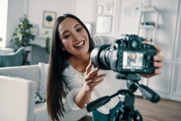 Checking media equipment. Attractive young woman adjusting video camera and smiling while making new video for her blog                 - Photo, Image