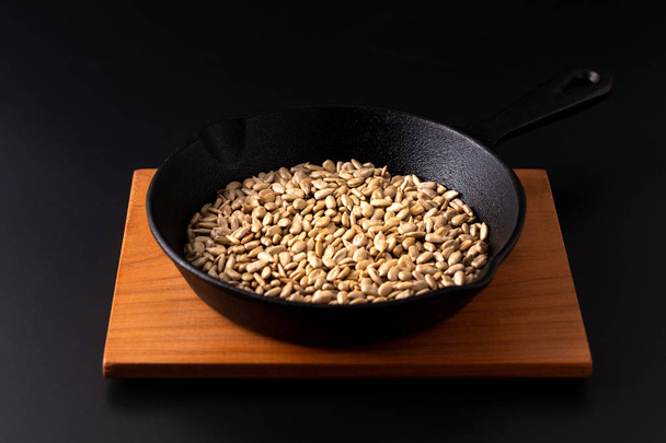 Концепция здорового питания жареные органические семена подсолнечника в сковороде
  - Фото, изображение