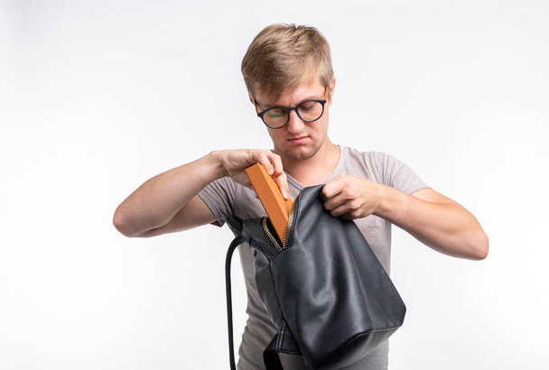 Bildung, Universität, Volkskonzept - männlicher Student packt sein Ding zum Studium in die Tasche - Foto, Bild