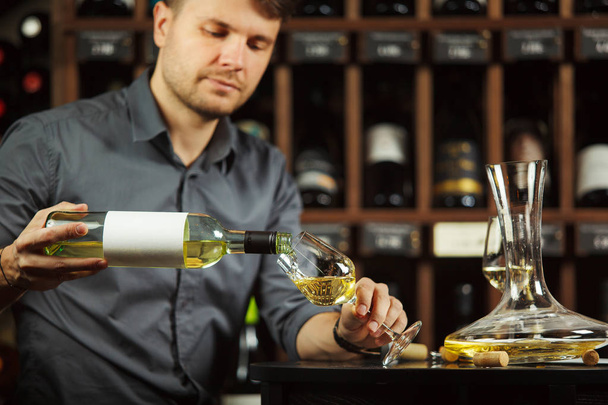 Sommelier pouring white wine from bottle in glass - Foto, Imagen