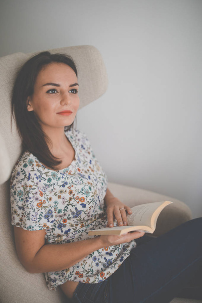 Cute young woman reading a book in a designer chair  - Фото, зображення
