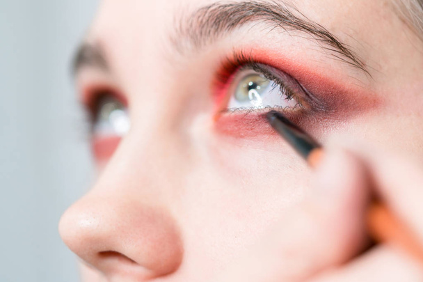 Performing eye makeup close-up. Bright red eyeshadow - Foto, imagen