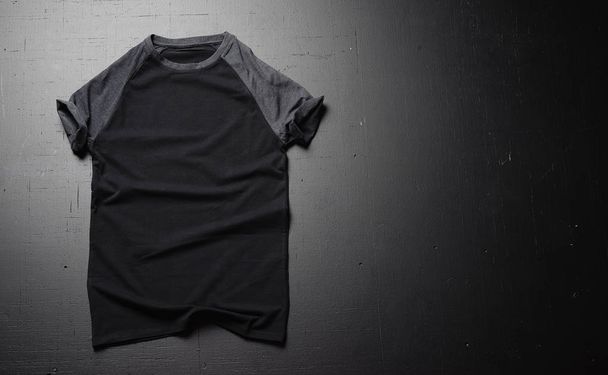 Empty vintage t-shirt lies on a black wooden table background. Front view of American Hipsters retro classic clothes. Copy paste space - Φωτογραφία, εικόνα