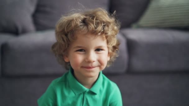 Slow motion portrait of cute little boy looking at camera and smiling at home - Metraje, vídeo
