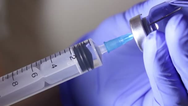 Doctors hands fill the syringe with vaccine, preparing for the injection of the injection to the patient. - Materiał filmowy, wideo