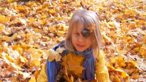 Little cute girl throwing up leaves at park in autumn - Footage, Video
