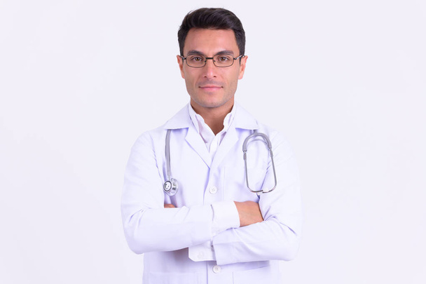 Young handsome Hispanic man doctor with arms crossed - 写真・画像
